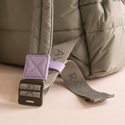 Close-up of a backpack strap with a purple buckle and 'Rov' branding on a beige background.
