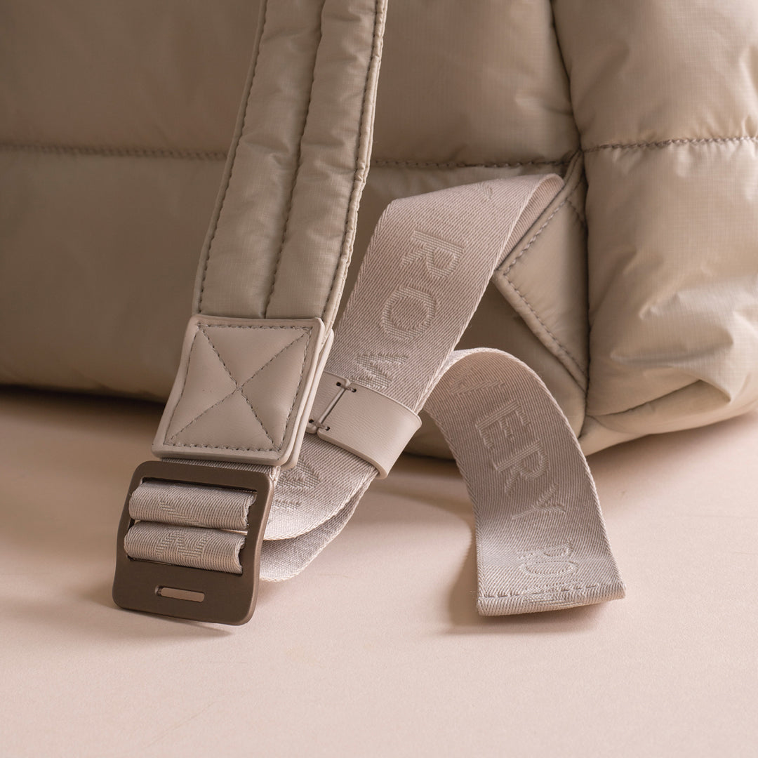 Close-up of a beige backpack with a strap on a matching background