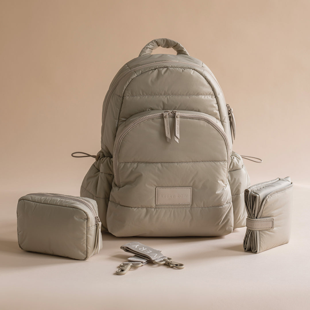Light gray backpack with matching pouches and keychain on a beige background