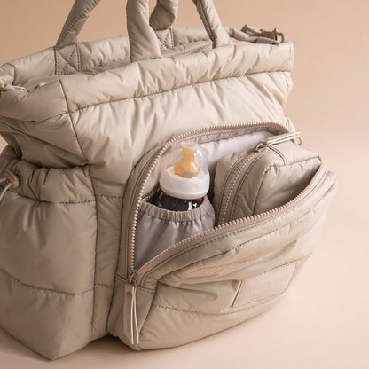 Beige quilted bag with a bottle inside on a beige background