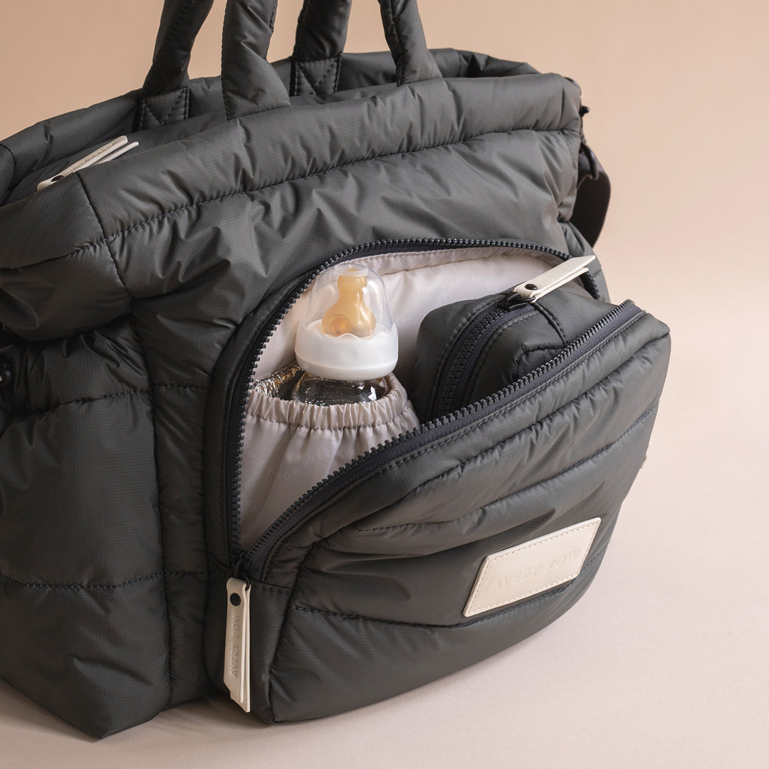 Gray insulated bag with baby bottle and accessories on a beige background