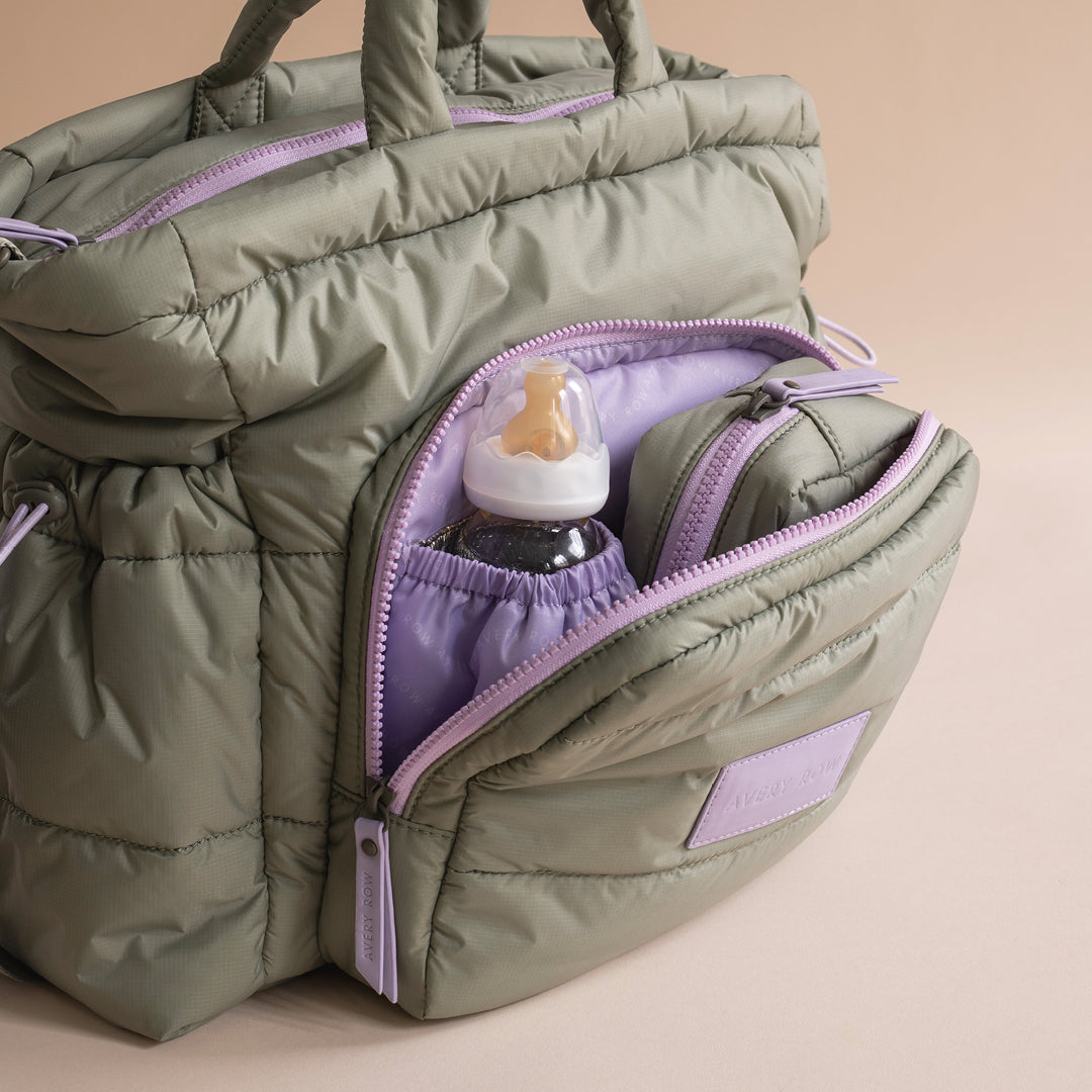 Green puffer bag with a baby bottle inside on a beige background
