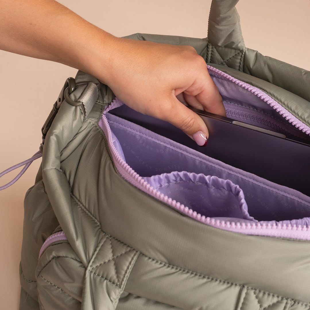 Person reaching into a green quilted bag with purple interior