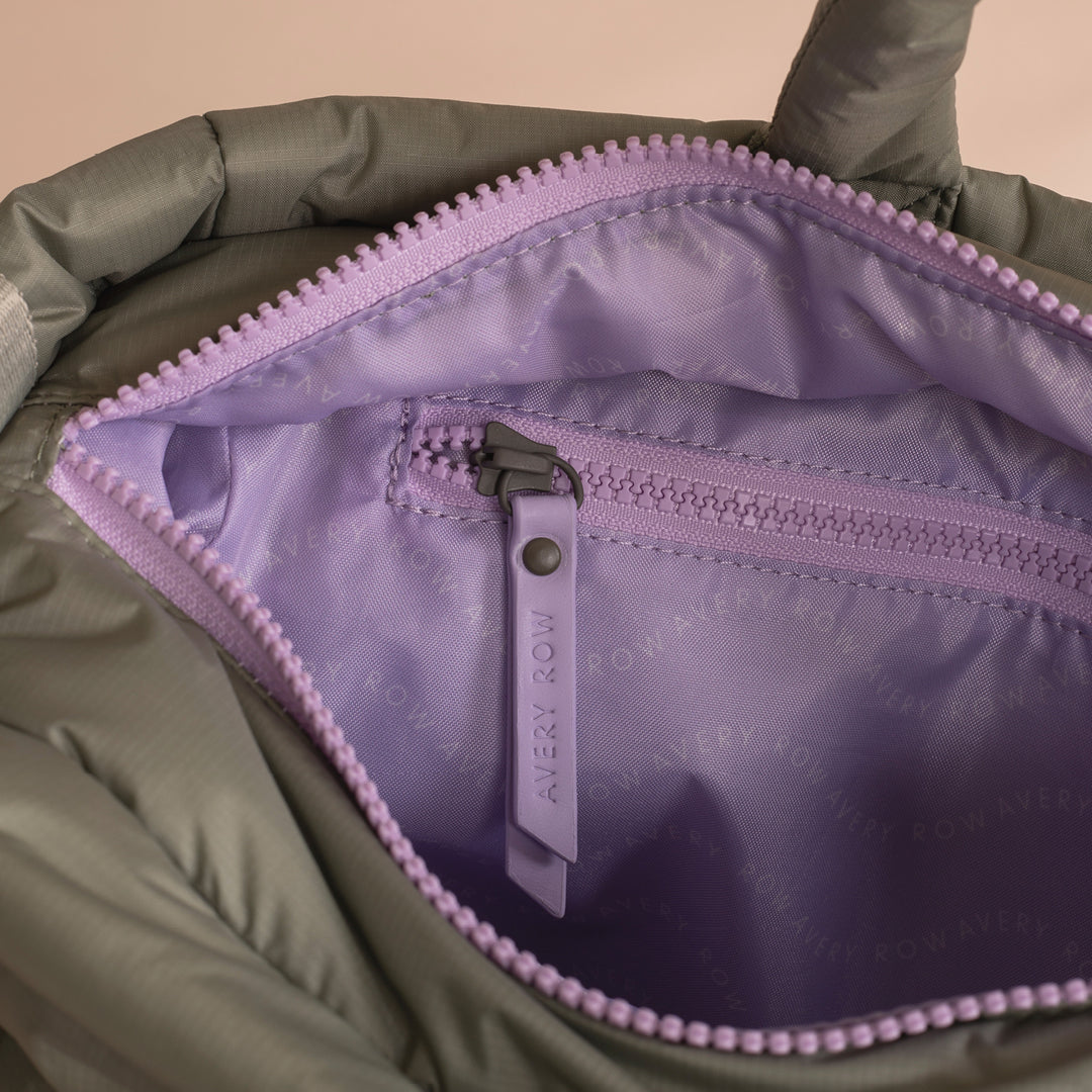 Close-up of a green jacket with a purple zipper, showing the brand 'Avery Row'.