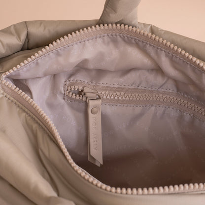 Close-up of a beige bag with a zipper, featuring the brand 'Avery Rose'.