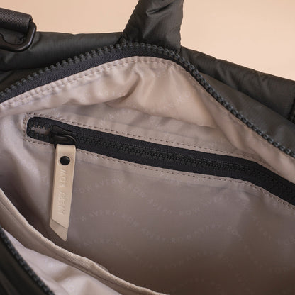 Close-up of a black zipper on a gray bag with a visible brand label.