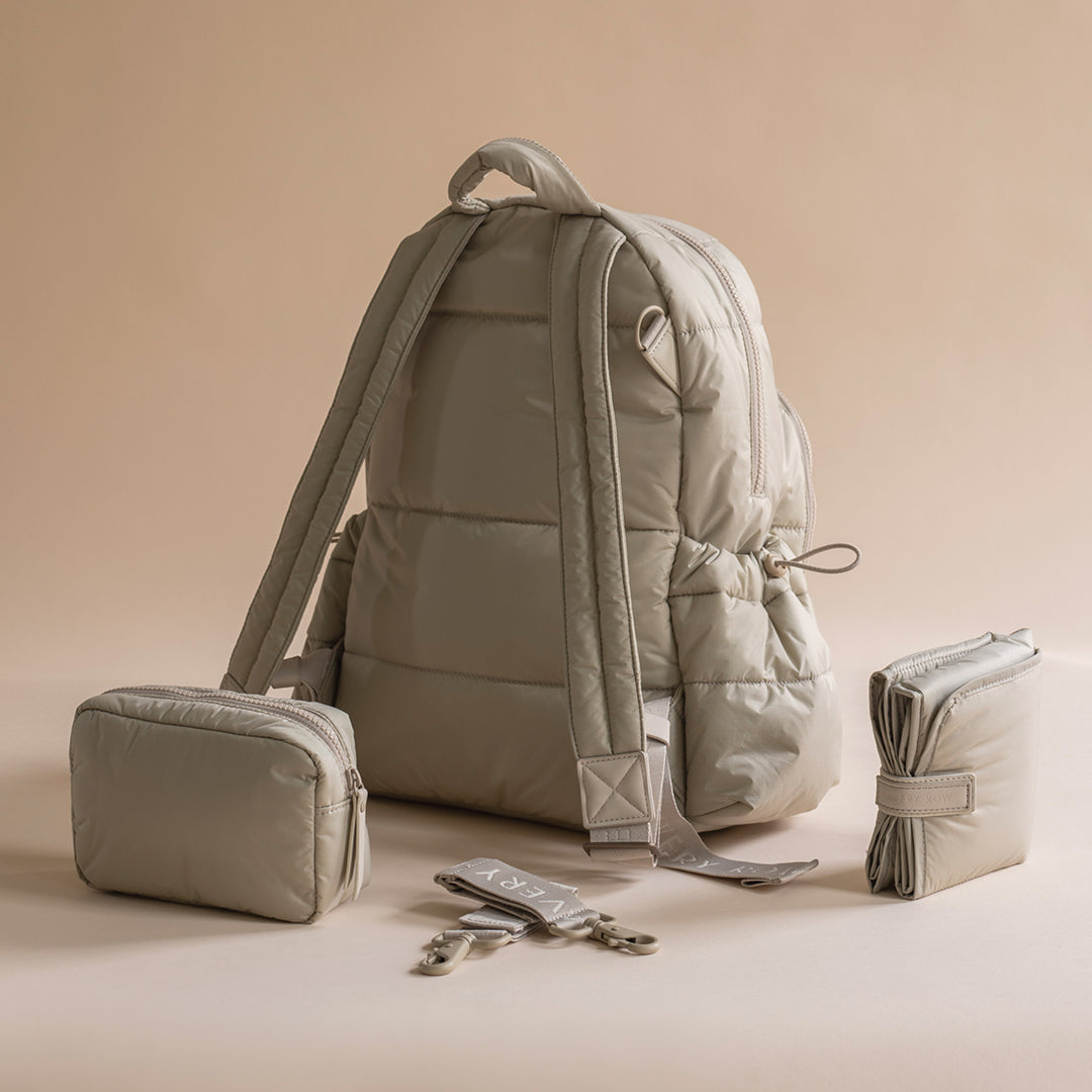 Beige backpack with smaller bags and accessories on a beige background