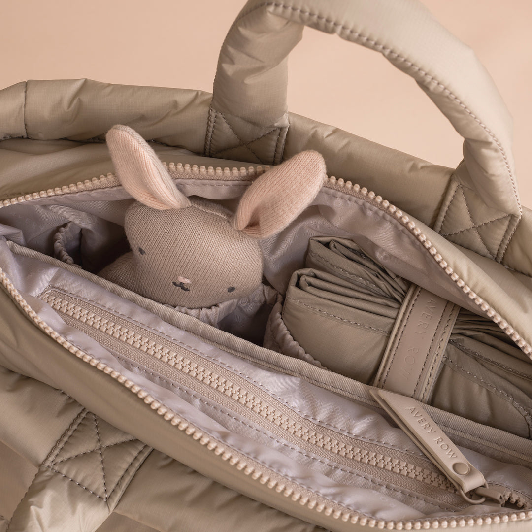 Beige quilted bag with a plush toy inside on a beige background