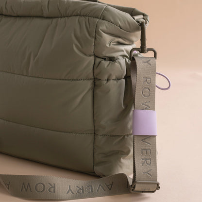 Close-up of a green puffer jacket with a visible brand tag on a beige background