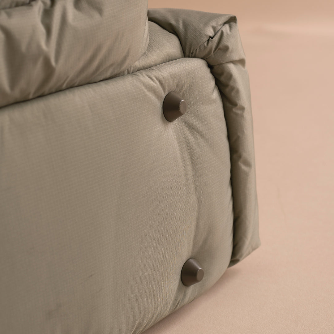 Close-up of a beige cushion with metallic buttons on a beige background