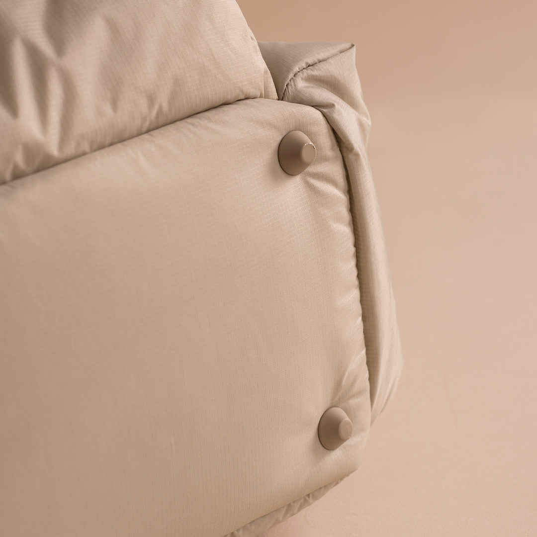 Close-up of a beige quilt with button details on a beige background