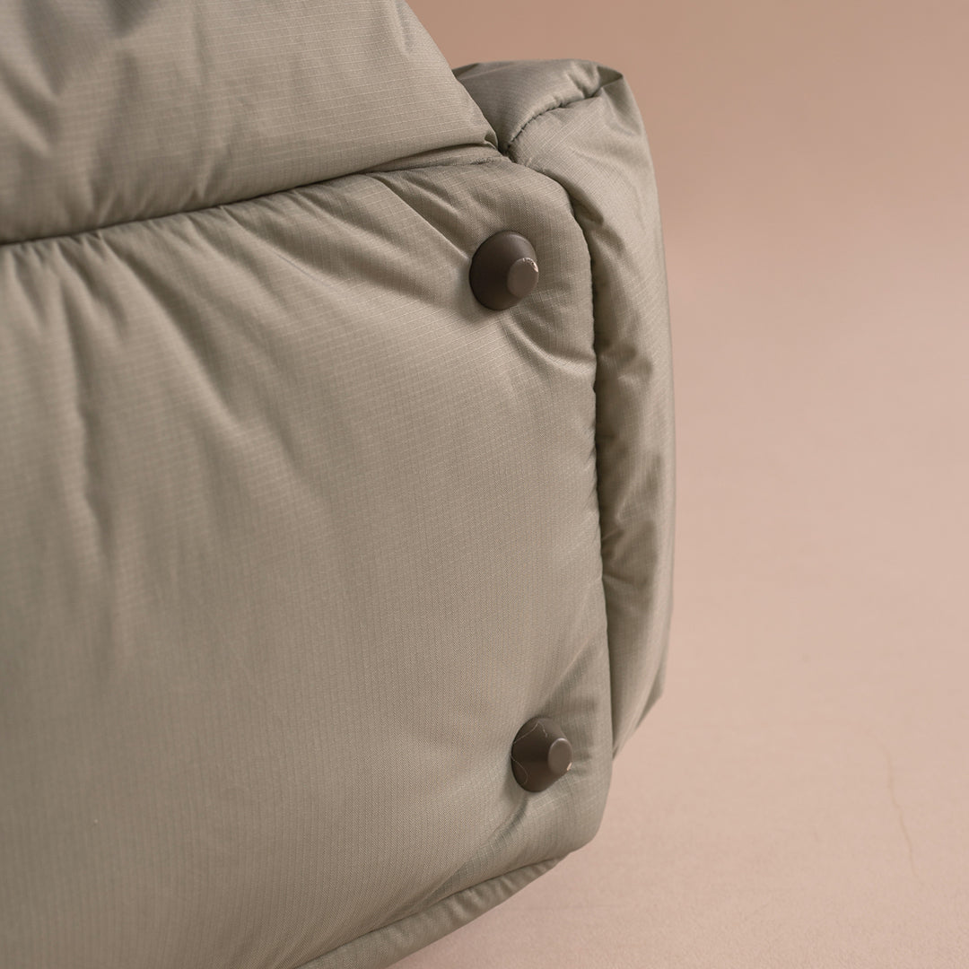 Close-up of a beige puffer jacket with buttons on a beige background