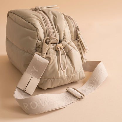 Beige puffer bag with matching strap on a beige background