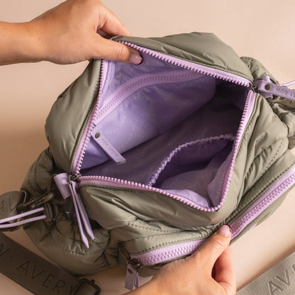 Green backpack with purple interior being held open by a person's hands.