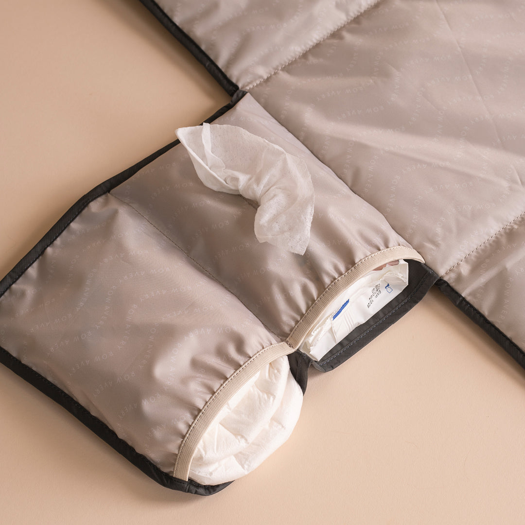 Close-up of a folded beige blanket with black edges on a beige surface.