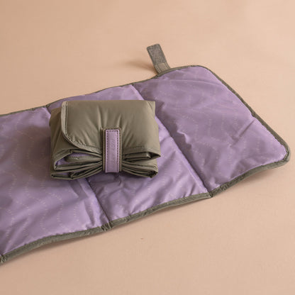Purple quilt with a folded green fabric item on a beige background