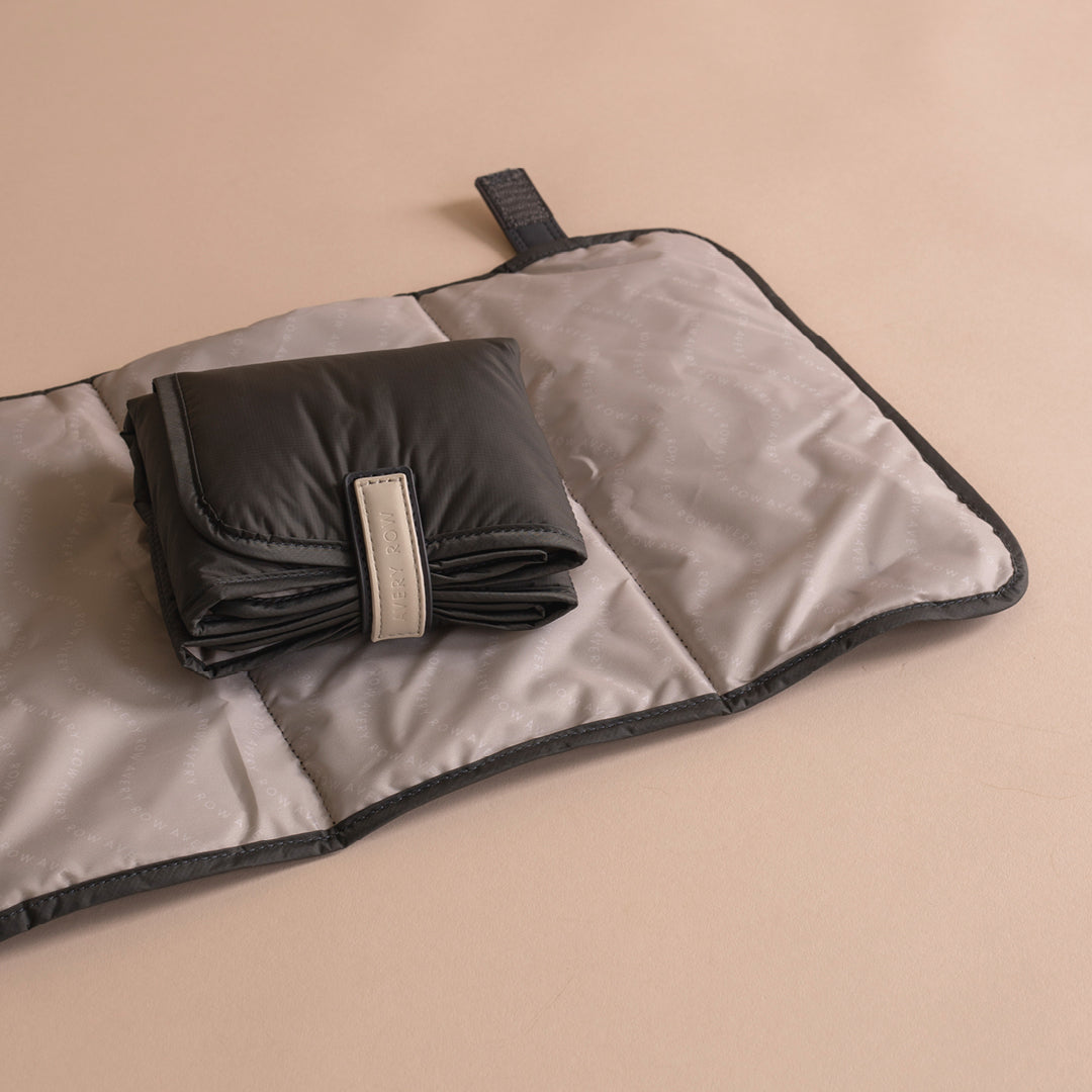 Folded black blanket on a gray blanket with a beige background