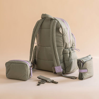 Green backpack with smaller bags on a beige background