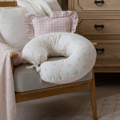 Breastfeeding pillow on a chair with a wooden dresser in the background