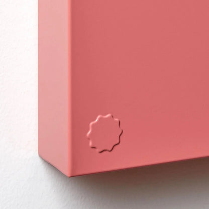 Close-up of a pink product with a logo on a light gray background