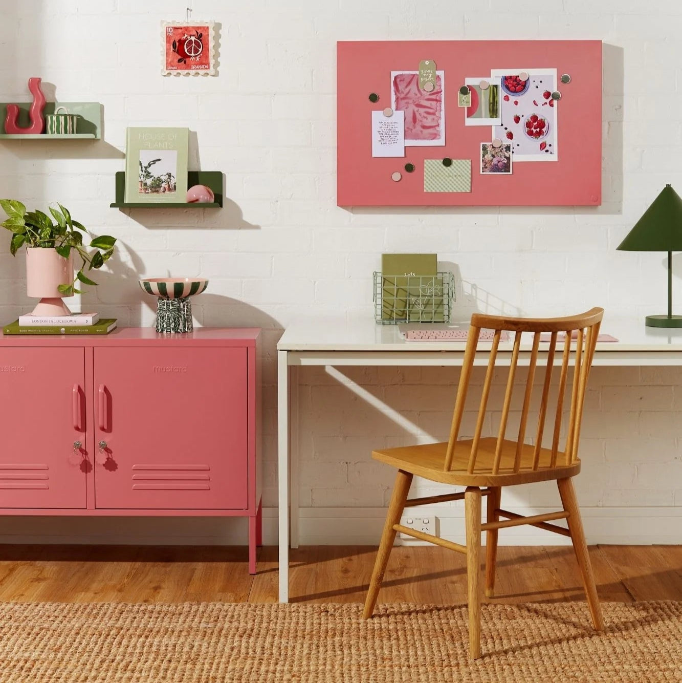 Home office with pink storage unit, wooden chair, and white wall.