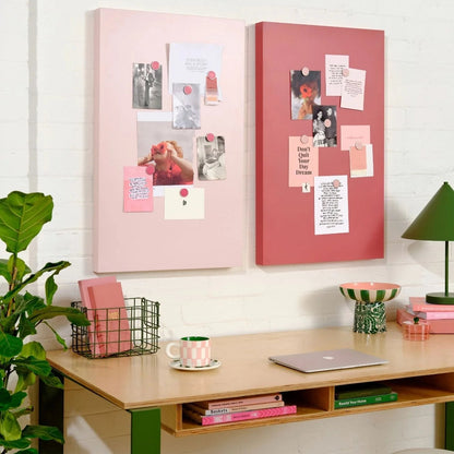 Desk with pink and red magnetic boards, plants, and a lamp in a home office setting.