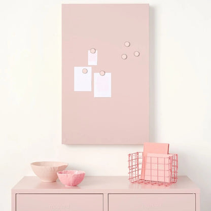 Pink cabinet with a pink memo board above it on a white wall.