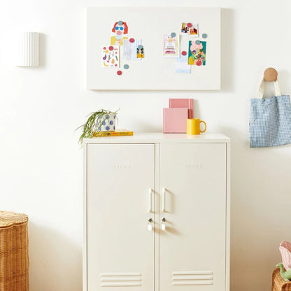 White cabinet with decorative items on a wooden floor in a room.