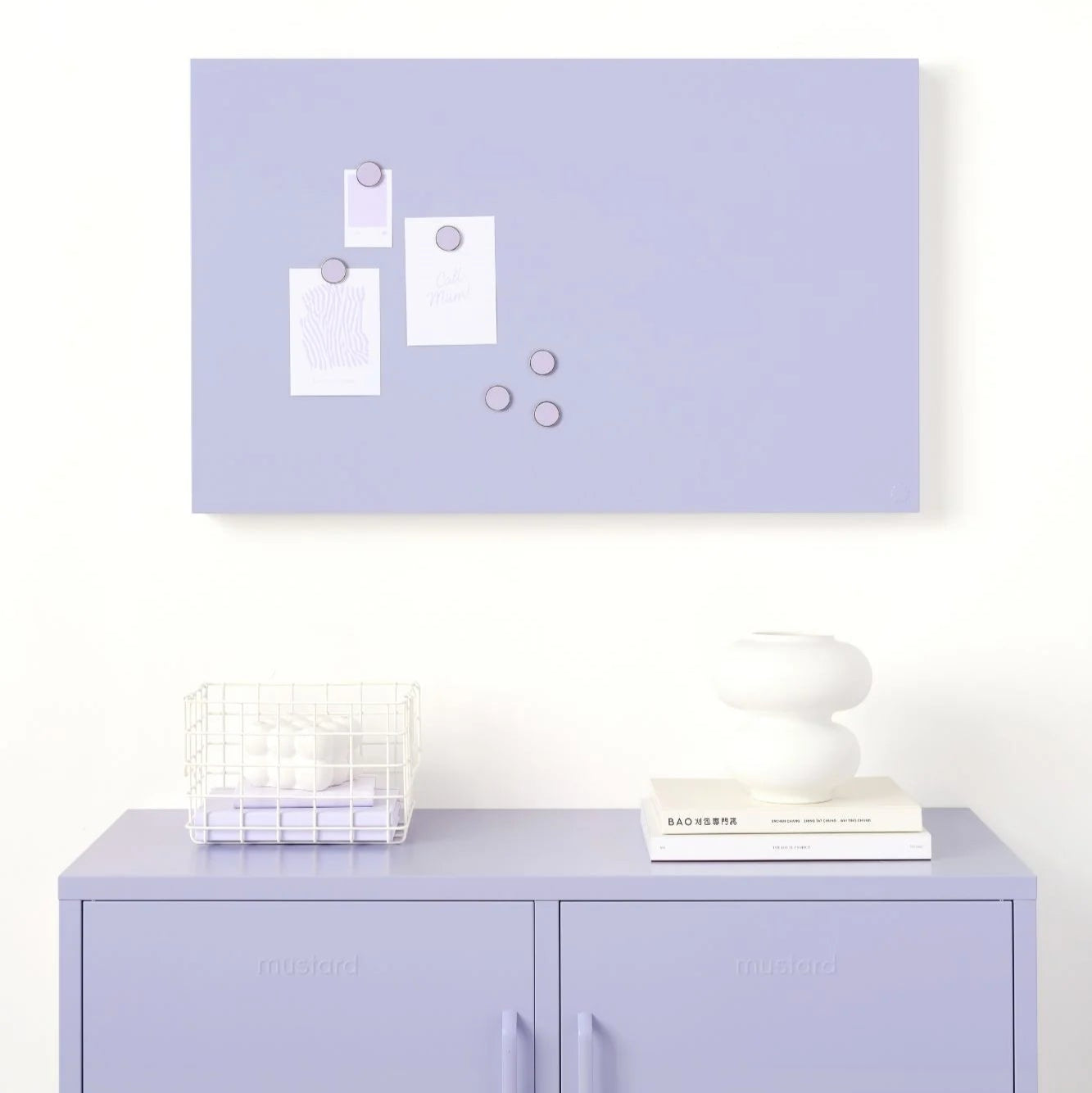 Light purple wall with a magnetic board and a cabinet below on a white background