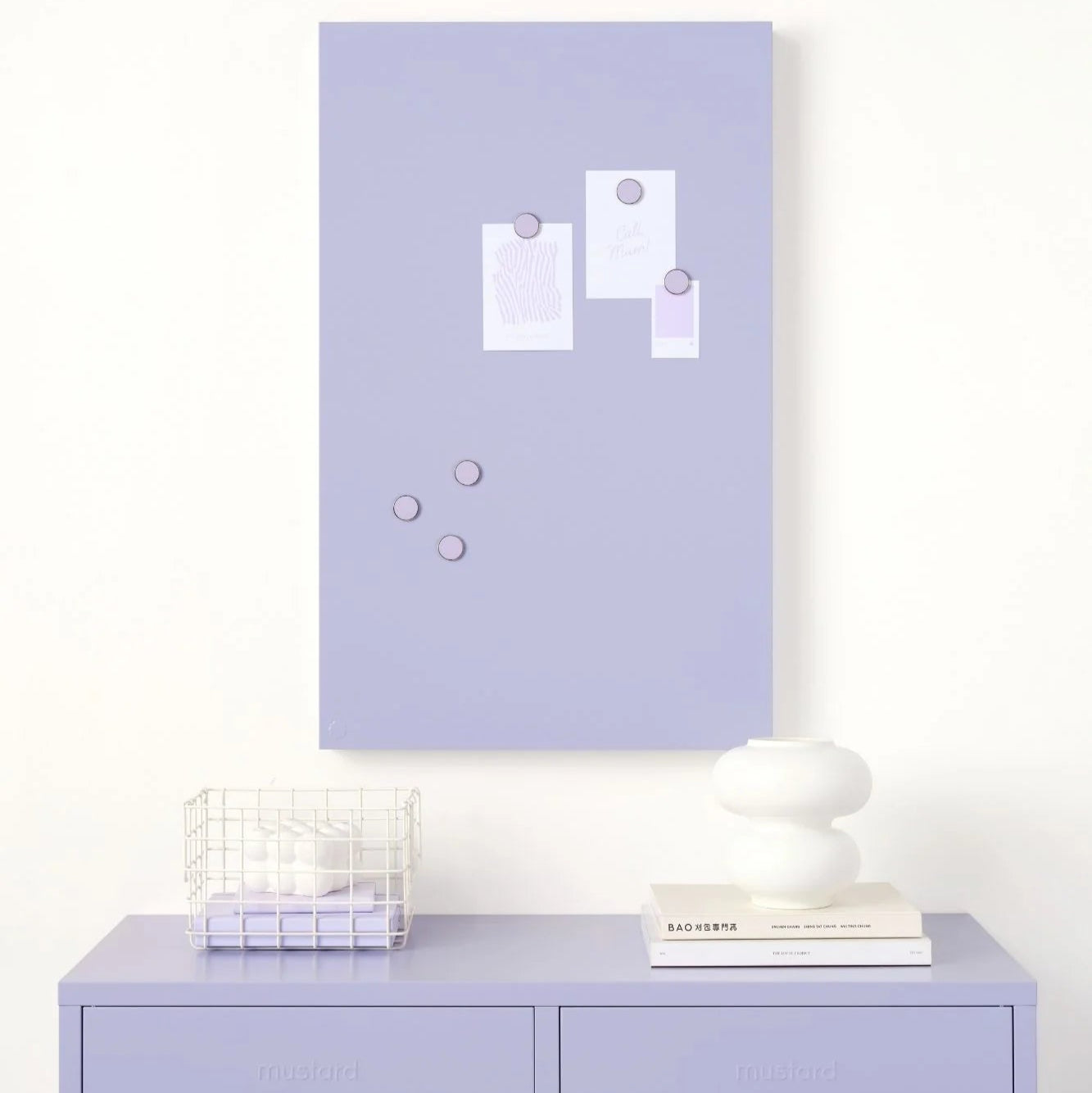 Lavender wall with a magnetic board and cabinet below