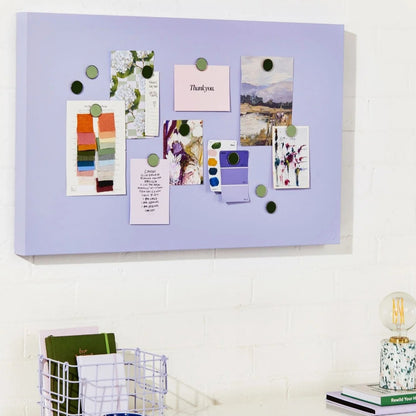 Purple magnetic board with various notes and photos on a white desk.