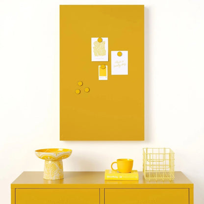 Yellow cabinet with a matching yellow magnetic notice board on a white wall.