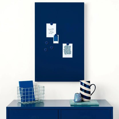 Blue magnetic board on a white wall above a blue cabinet with decorative items.