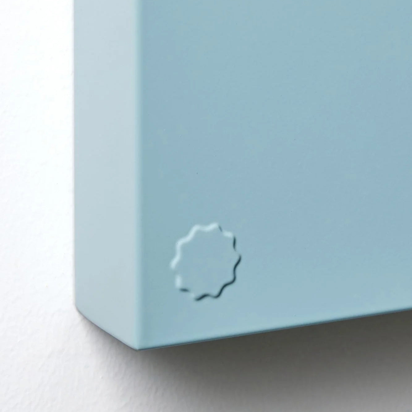 Close-up of a light blue rectangular object with a circular logo on a white background