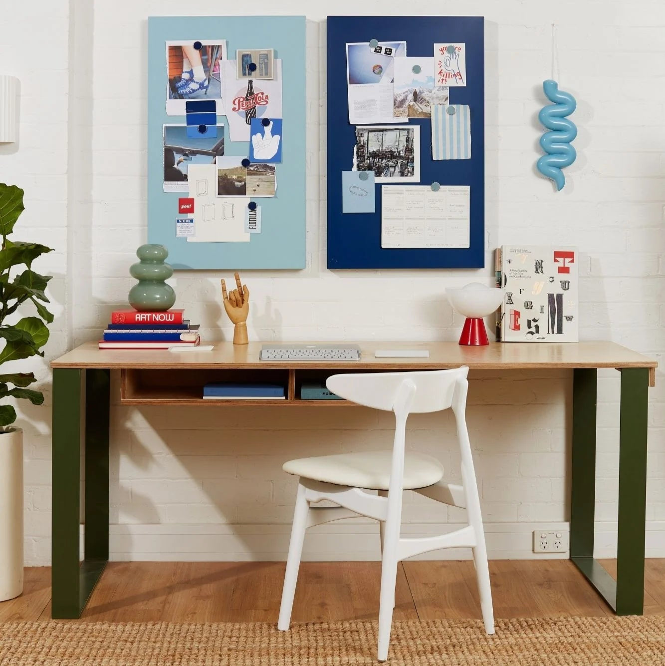 Home office setup with a desk, chair, and decorative elements on a white wall.