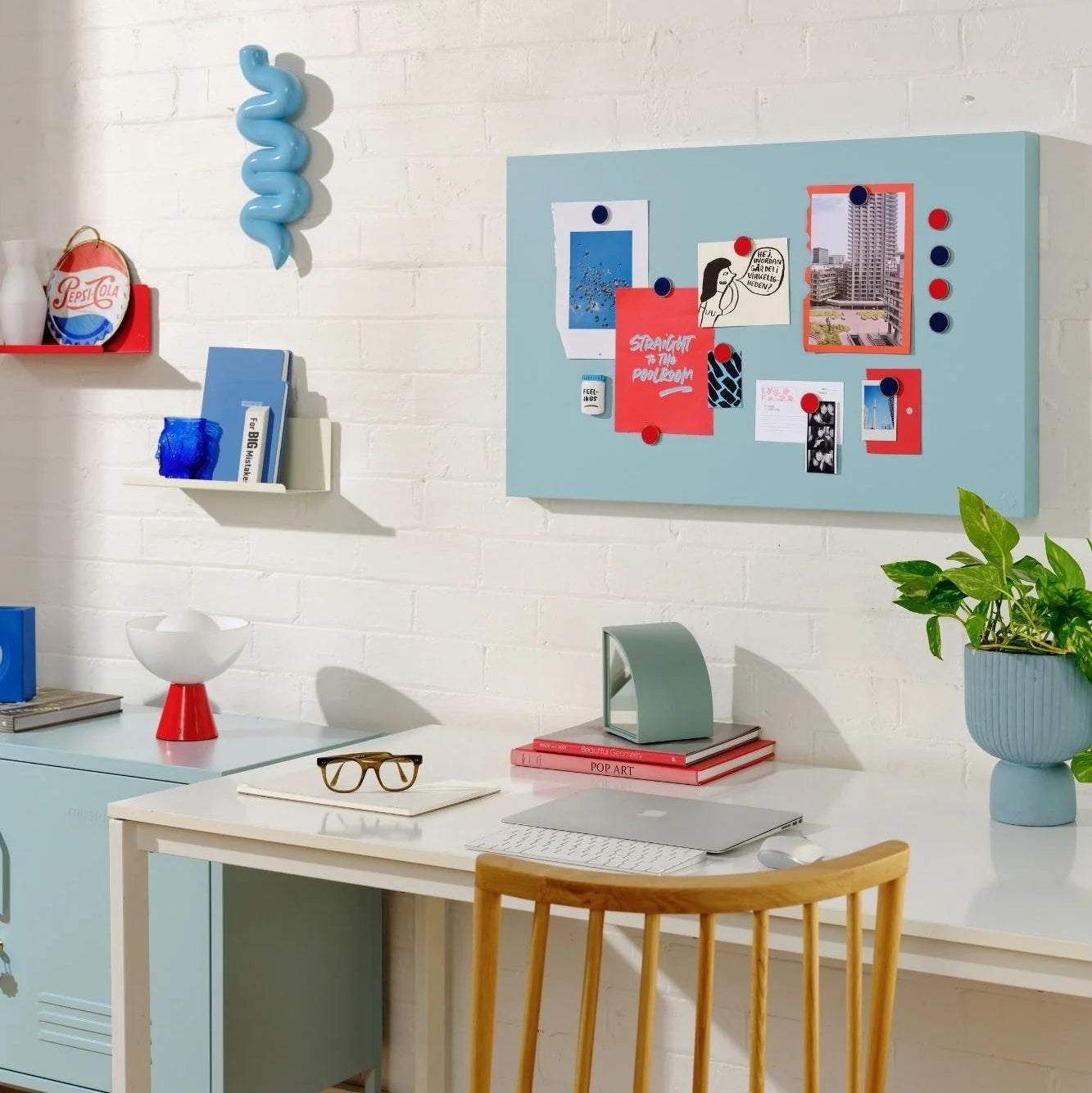 Modern home office with a desk, chair, and decorative items on a white brick wall.