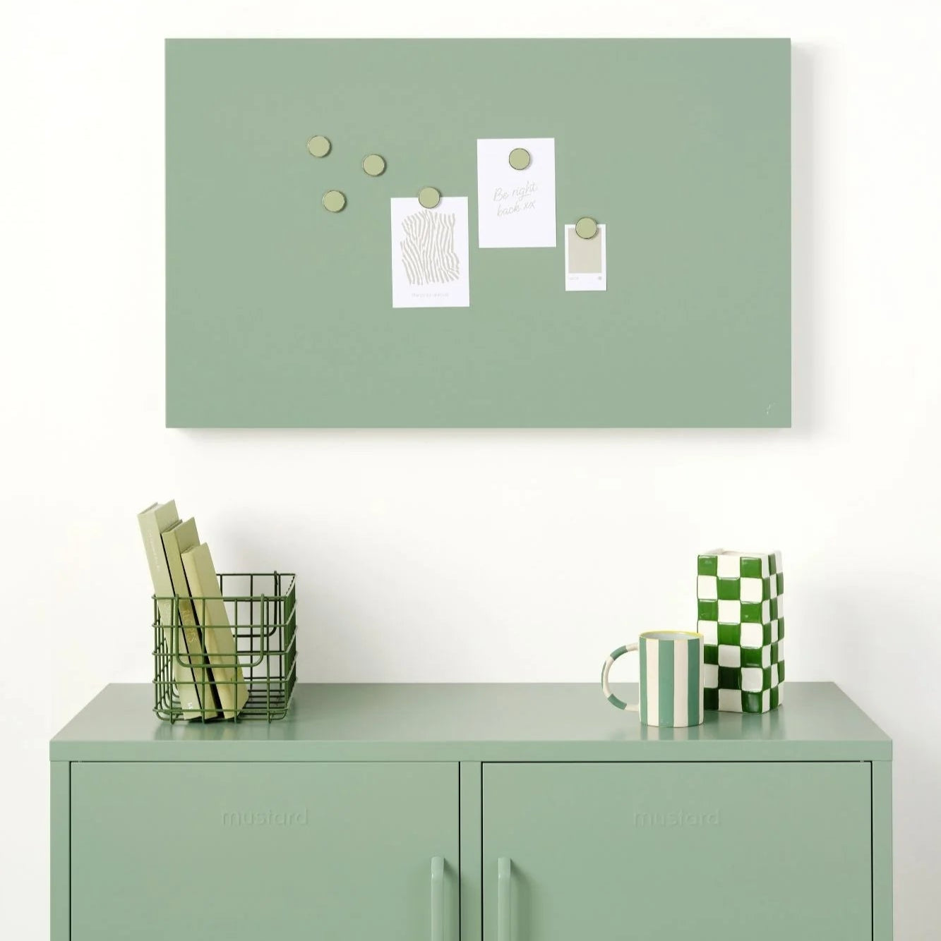 Green bulletin board with decorative items above a green locker.