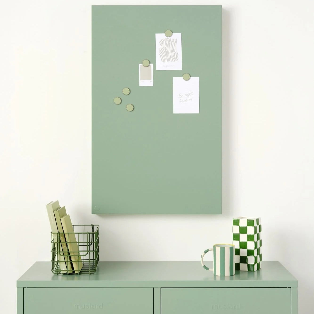 Green cabinet with a green magnetic notice board above it on a white wall.
