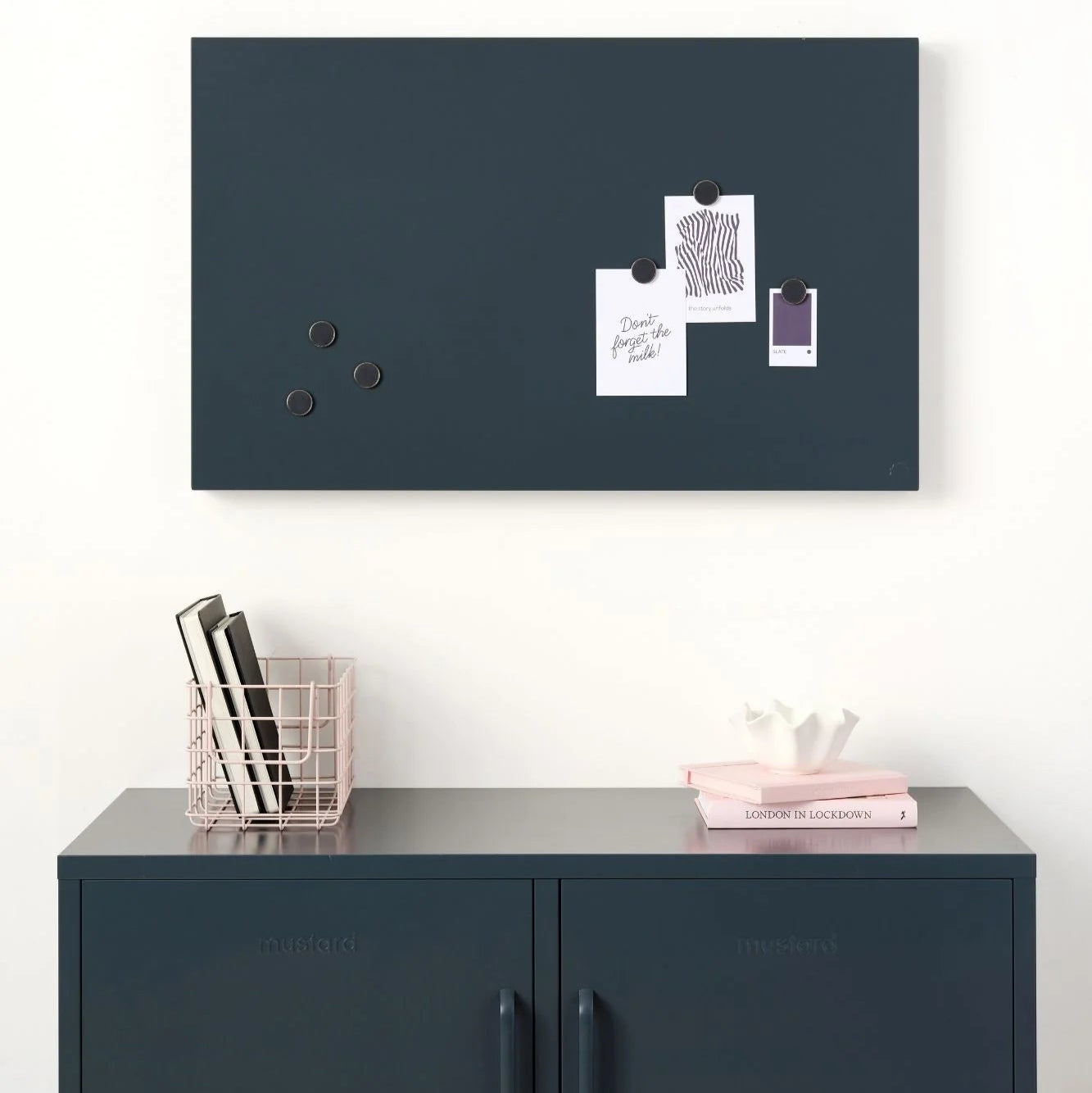 Navy blue magnetic notice board with pinned papers above a matching cabinet.