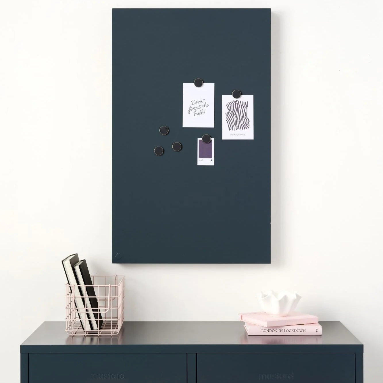 Navy magnetic board on a white wall above a navy locker.
