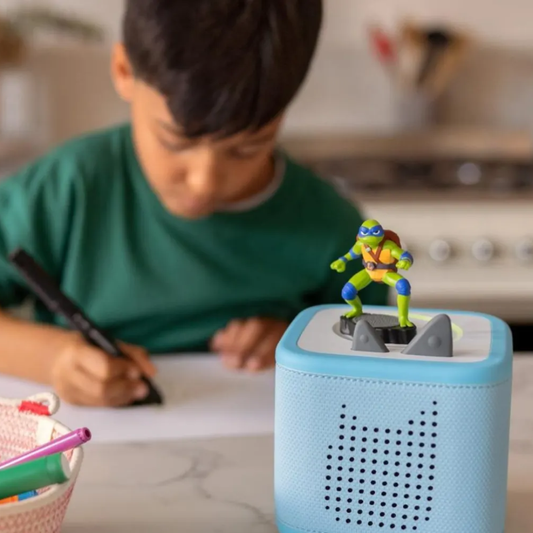 Child drawing with a toy figure on top of a blue device in a kitchen setting