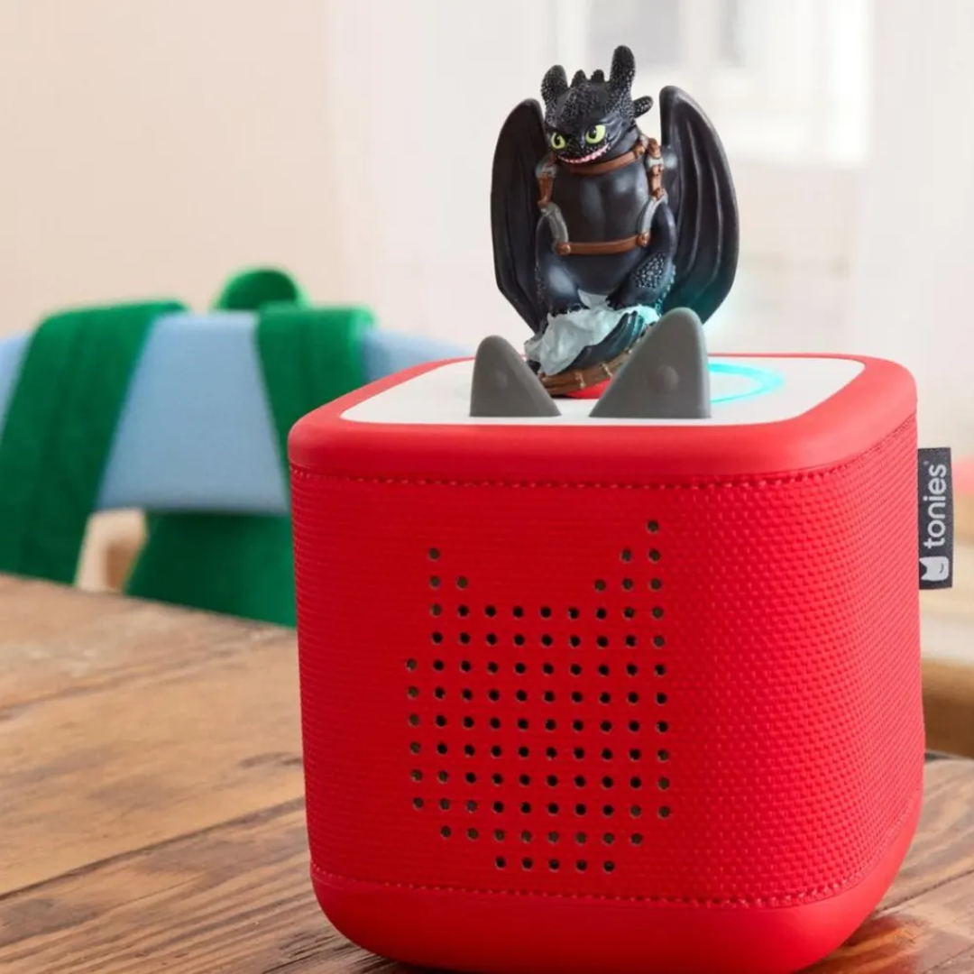 Red speaker with a dragon figurine on top, placed on a wooden surface.