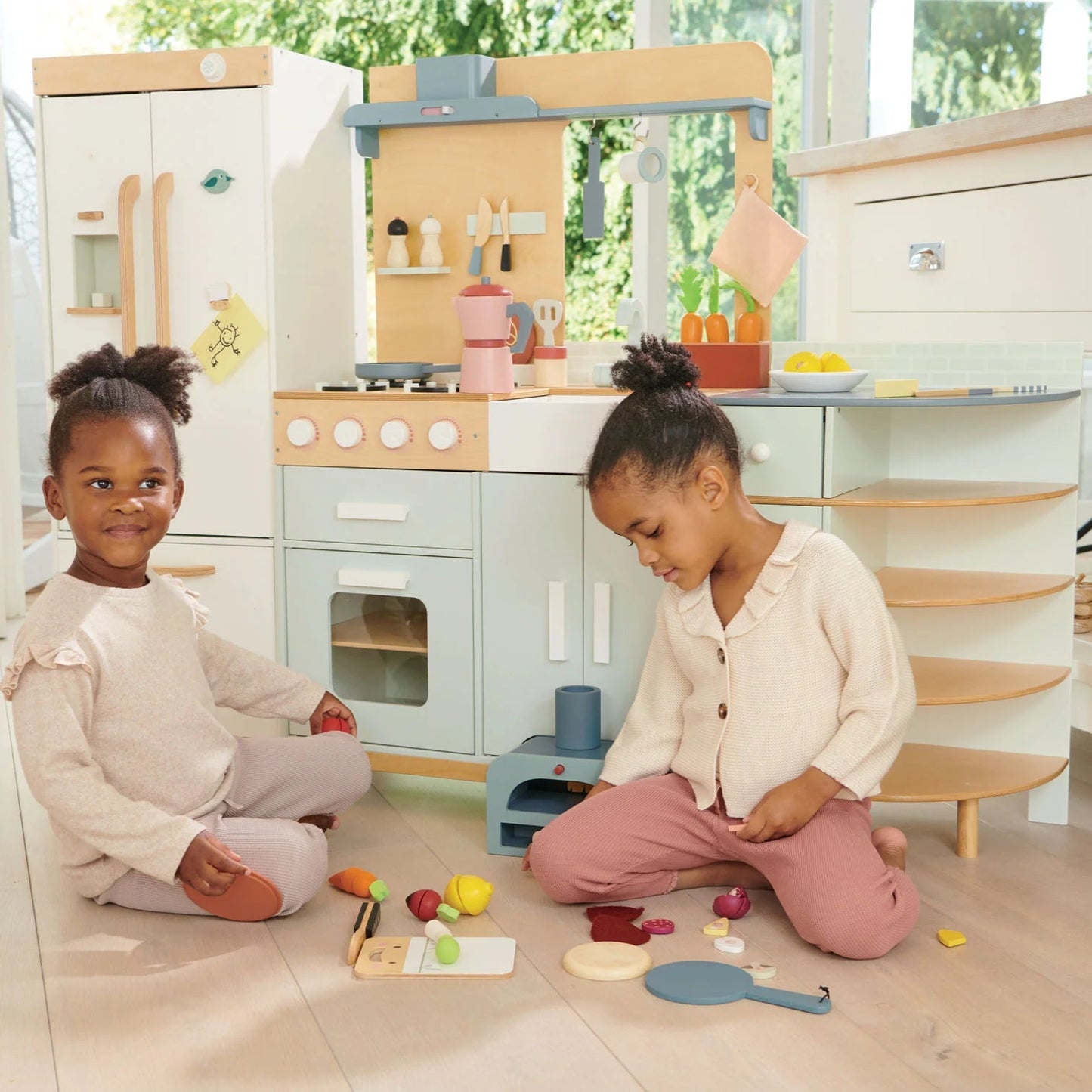 Two children playing with toys in a play kitchen set.