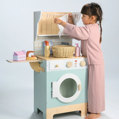 Child playing with a toy washing machine and dryer set on a light gray background
