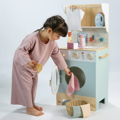 Child playing with a toy washing machine and dryer set on a light background
