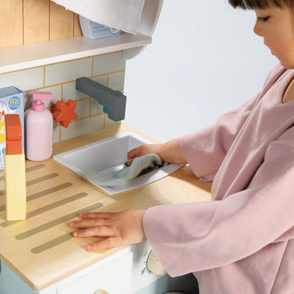 Child playing with a toy kitchen set, washing dishes.