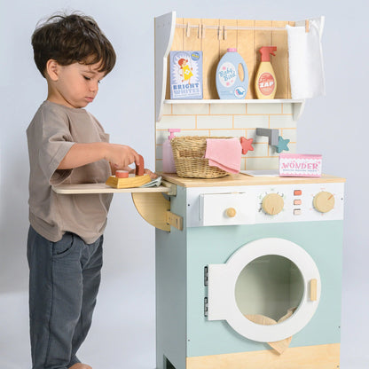 Child playing with a toy washing machine and dryer set on a light gray background
