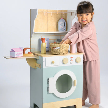 Child playing with a toy washing machine and dryer set on a light gray background