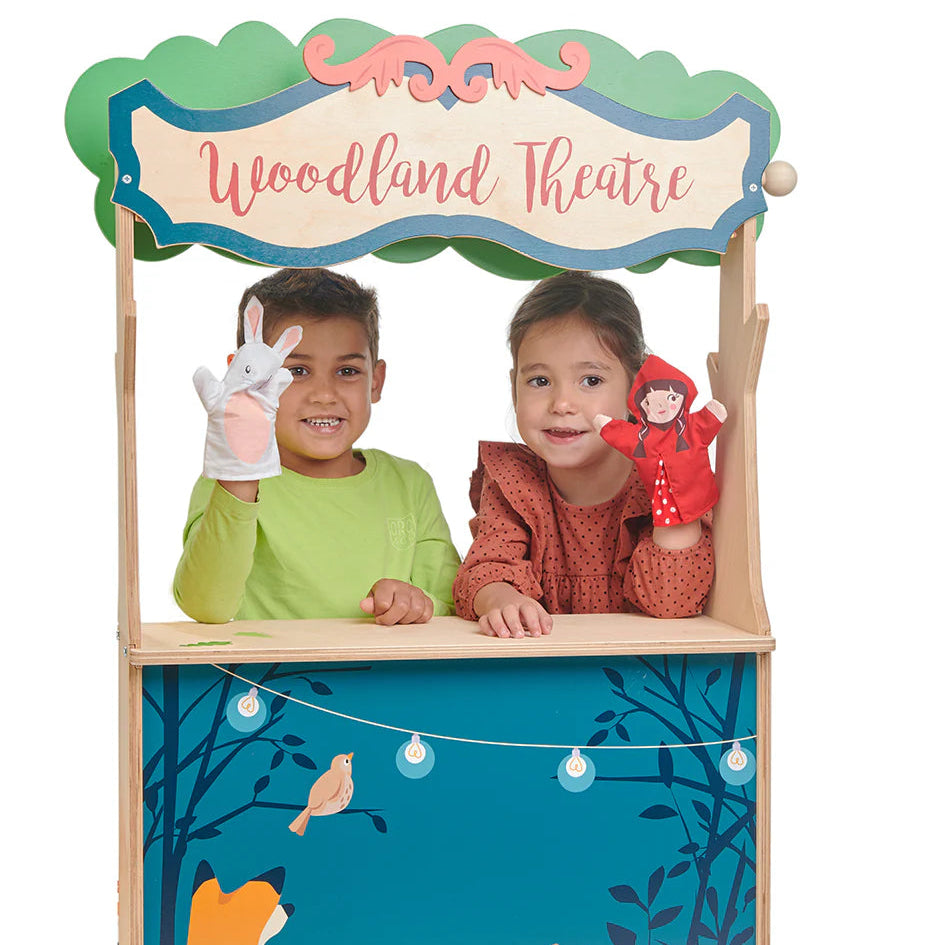Children playing with a wooden puppet theatre set in a forest design.