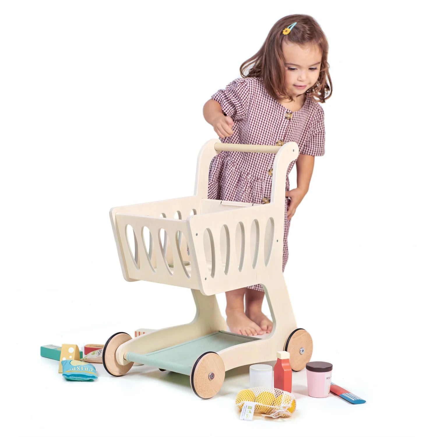 Child playing with a toy shopping cart on a white background